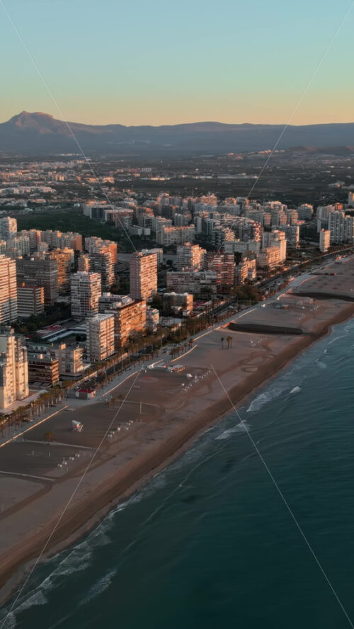 Aerial view of the beach and the buildings along the coastline in Alicante, Spain at sunset. Vertical - Starpik Stock