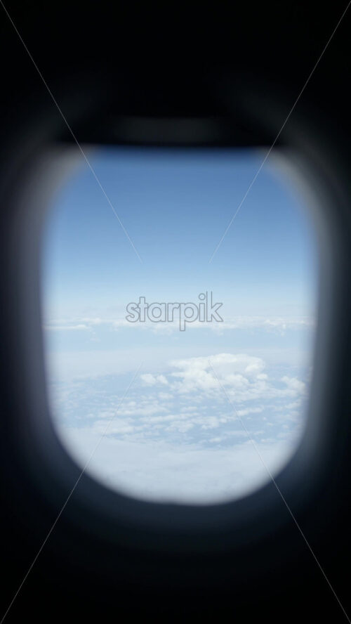 Aerial view of white, fluffy clouds from an airplane window - Starpik Stock