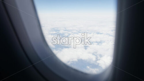 Aerial view of white, fluffy clouds from an airplane window - Starpik Stock