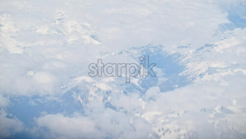 Aerial view of white, fluffy clouds from an airplane window - Starpik Stock