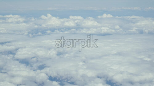 Aerial view of white, fluffy clouds from an airplane window - Starpik Stock