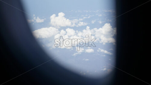 Aerial view of white, fluffy clouds from an airplane window - Starpik Stock