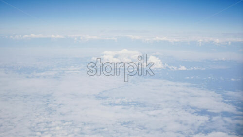 Aerial view of white, fluffy clouds from an airplane window - Starpik Stock