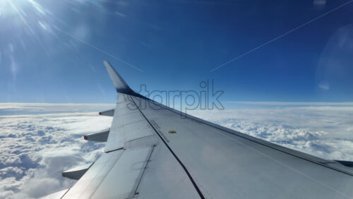 Aircraft wing gliding above layered clouds viewed from the window seat - Starpik Stock