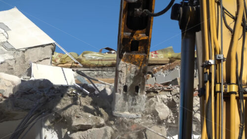 An excavator demolishing concrete building with hydraulic breaker in daylight - Starpik Stock