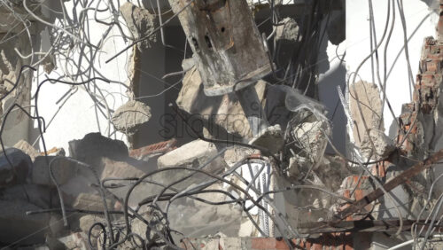 An excavator demolishing concrete building with hydraulic breaker in daylight - Starpik Stock