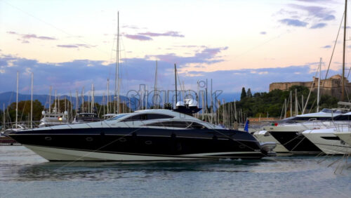 Antibes, France – July 2, 2025: Black and white yacht docking in the Port Vauban with the Fort Carre on the background at sunset - Starpik Stock