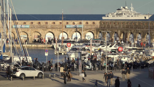 Antibes, France – July 2, 2025: Scenic coastal view featuring a luxury yacht, historic stone arches, and a colourful carousel - Starpik Stock