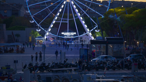 Antibes, France – June 7, 2025: Multiple white boats docked in the Port Vauban with the illuminated ferris wheel on the background in the evening - Starpik Stock