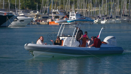 Antibes, France – June 7, 2025: People in a moving boat waving at the camera in the Port Vauban in daylight - Starpik Stock