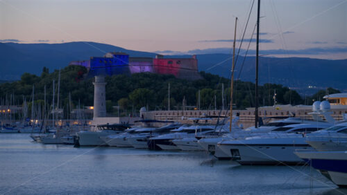 Antibes, France – June 8, 2025: Boats docked in Port Vauban with Fort Carre illuminated on the background in the evening - Starpik Stock