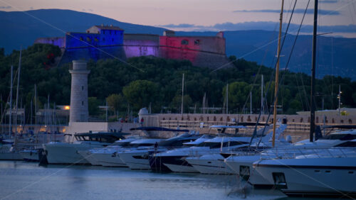 Antibes, France – June 8, 2025: Boats docked in Port Vauban with Fort Carre illuminated on the background in the evening - Starpik Stock