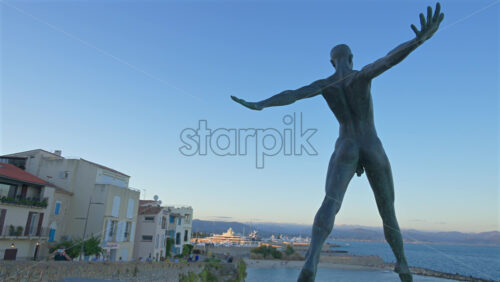 Antibes, France – June 8, 2025: Bronze sculpture “Grand Defi” by Nicolas Lavarenne with boats docked in the background - Starpik Stock