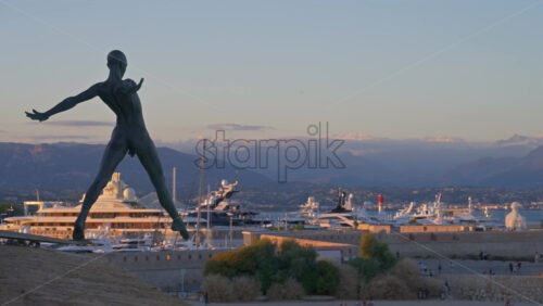 Antibes, France – June 8, 2025: Bronze sculpture “Grand Defi” by Nicolas Lavarenne with boats docked in the background - Starpik Stock
