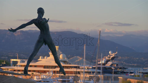 Antibes, France – June 8, 2025: Bronze sculpture “Grand Defi” by Nicolas Lavarenne with boats docked in the background - Starpik Stock