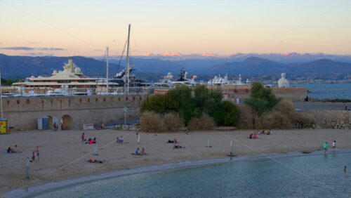 Antibes, France – June 8, 2025: People walking on the coast of the city with The Nomad by Jaume Plensa sculpture on the background - Starpik Stock