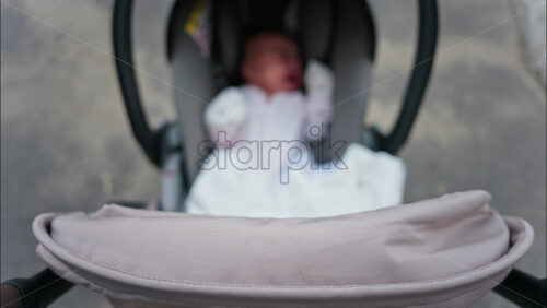 Blurred view of a baby resting in a stroller while on a walk on the street - Starpik Stock