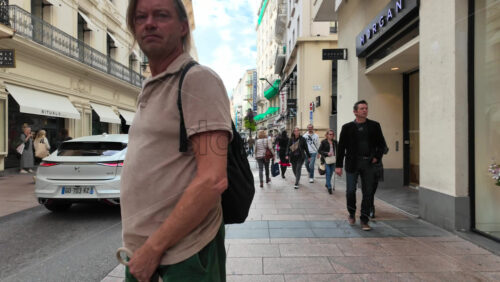 Cannes, France – August 4 2025: People holding bags walking on a shopping street - Starpik Stock