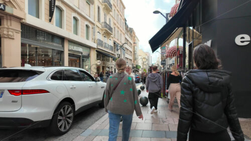 Cannes, France – August 4 2025: People holding bags walking on a shopping street - Starpik Stock