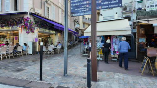 Cannes, France – August 4 2025: People walking near terraces, on the streets of the city with busses parked on the other side of the road - Starpik Stock