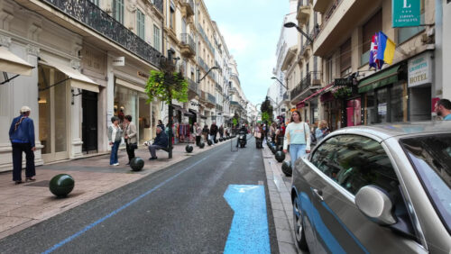Cannes, France – August 4 2025: People walking on a shopping street with clothing racks lining the street and people browsing garments - Starpik Stock