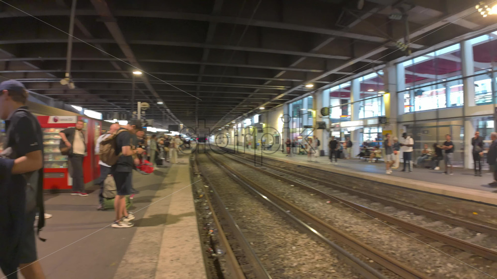 Cannes, France – July 10, 2025: Passengers waiting as regional train pulls through a covered station platform - Starpik Stock