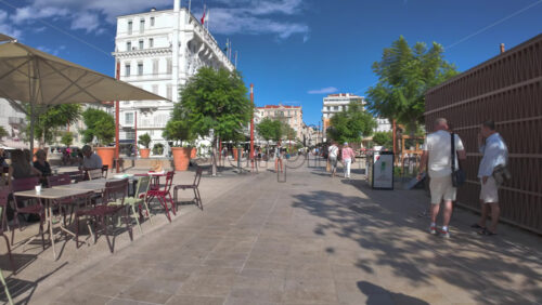 Cannes, France – July 10, 2025: People walking on the streets of the city, near terraces and a carousel in daylight - Starpik Stock