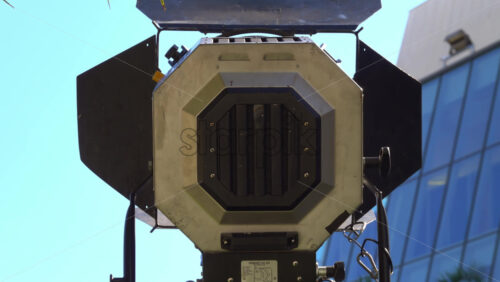 Cannes, France – July 2, 2025: Close-up of a professional film light with set against a clear blue sky and a modern glass building - Starpik Stock