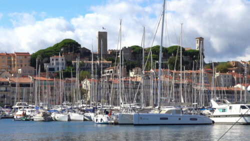 Cannes, France – July 2, 2025: Distant view from the Old Port of a Cannes sign written on a mountain near the Notre Dame d’Esperance church and the Museum of World Explorations - Starpik Stock