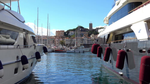 Cannes, France – July 2, 2025: Distant view from the Old Port of the flag of France waving on top of the Museum of World Explorations near green trees - Starpik Stock