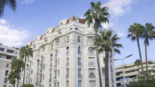 Cannes, France – June 22, 2025: Side view of the Hotel Barriere Le Majestic surrounded by palm tress in daylight - Starpik Stock