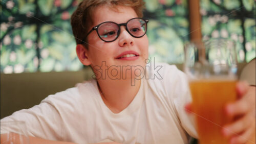 Chisinau, Moldova – August 18, 2025: Close up of a cheerful boy with glasses sitting at a table in a restaurant, smiling at the camera - Starpik Stock