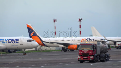 Chisinau, Moldova – July 1, 2025: A red fuel or service truck passing in front of different aircrafts at the Chisinau International Airport - Starpik Stock
