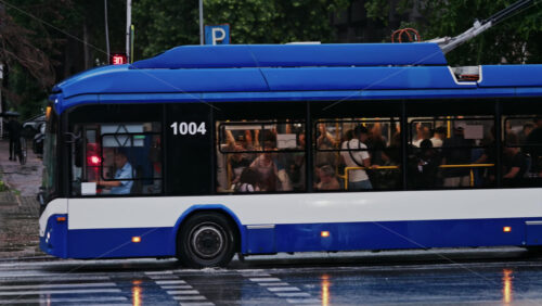 Chisinau, Moldova – June 11, 2025: A blue and white Trolleybus full of people moving on the streets of the city center in a rainy day - Starpik Stock