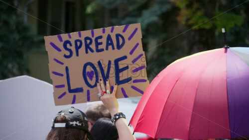 Chisinau, Moldova – June 15, 2025: Close up of hands holding a sign reading “Spread love” at the Pride March in the city center - Starpik Stock
