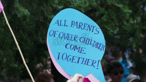 Chisinau, Moldova – June 15, 2025: Close up of hands holding sign reading “All parents of queer children come together!” at the Pride March in the city center - Starpik Stock