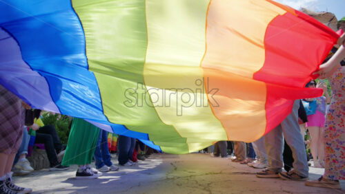 Chisinau, Moldova – June 15, 2025: Multiple people waving a long pride flag at the Pride March in the city center - Starpik Stock