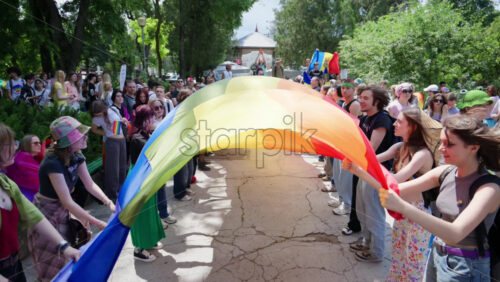 Chisinau, Moldova – June 15, 2025: Multiple people waving a long pride flag at the Pride March in the city center - Starpik Stock