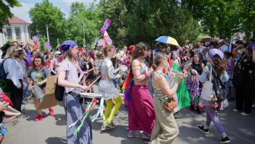 Chisinau, Moldova – June 15, 2025: People dancing, holding signs, and rainbow flags beating the drums and chanting at the Pride Parade in the city center - Starpik Stock