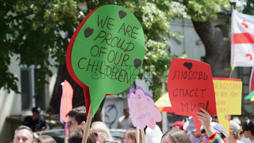Chisinau, Moldova – June 15, 2025: People marching and holding signs at the Pride Parade in the city center – Translation: “Love will save the world, Proud father of a trans son” - Starpik Stock