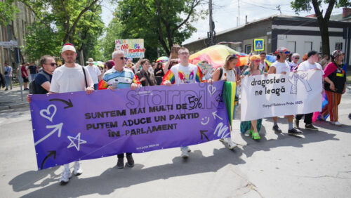 Chisinau, Moldova – June 15, 2025: People marching and holding signs at the Pride Parade in the city center – Translation: “We are more than 5%, we can bring a party into parliament, love unites us” - Starpik Stock