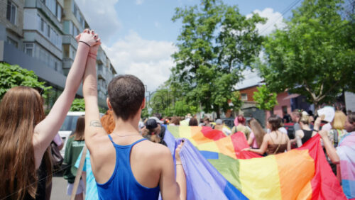 Chisinau, Moldova – June 15, 2025: People marching, holding a big rainbow flag at the Pride Parade in the city center - Starpik Stock