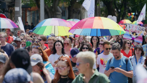 Chisinau, Moldova – June 15, 2025: People marching, holding signs and rainbow umbrellas at the Pride Parade in the city center - Starpik Stock