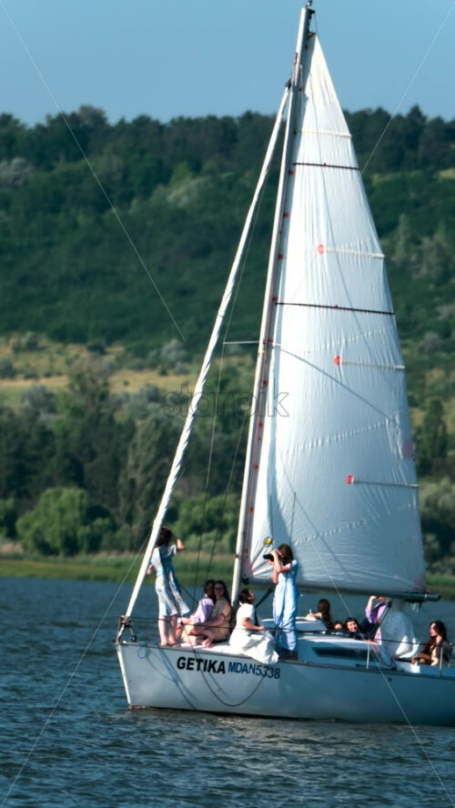 Chisinau, Moldova – June 17, 2025: A group of friends enjoying a relaxing sailing trip and taking pictures on a yacht during a sunny afternoon. Vertical - Starpik Stock