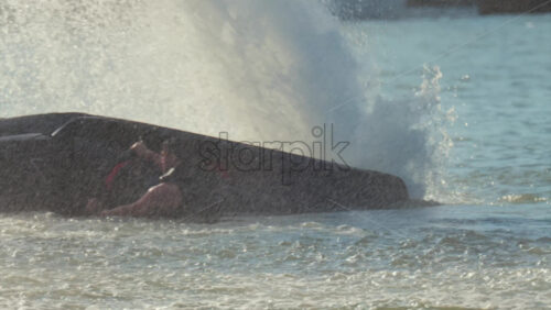 Chisinau, Moldova – June 17, 2025: A man in a black life vest doing tricks on a black jet ski at high speed across a calm body of water - Starpik Stock