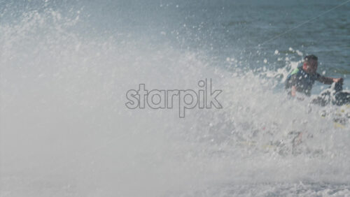 Chisinau, Moldova – June 17, 2025: A man in a black life vest riding a black jet ski at high speed across a calm body of water - Starpik Stock