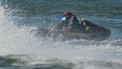 Chisinau, Moldova – June 17, 2025: A man in a black life vest riding a black jet ski at high speed across a calm body of water - Starpik Stock