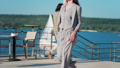 Chisinau, Moldova – June 17, 2025: Elegantly dressed man and woman walking on a scenic terrace with a view of a calm body of water - Starpik Stock