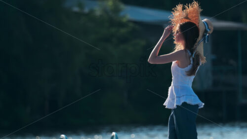 Chisinau, Moldova – June 17, 2025: Woman in a wide-brimmed straw hat with a ribbon, soaking in the late afternoon light - Starpik Stock