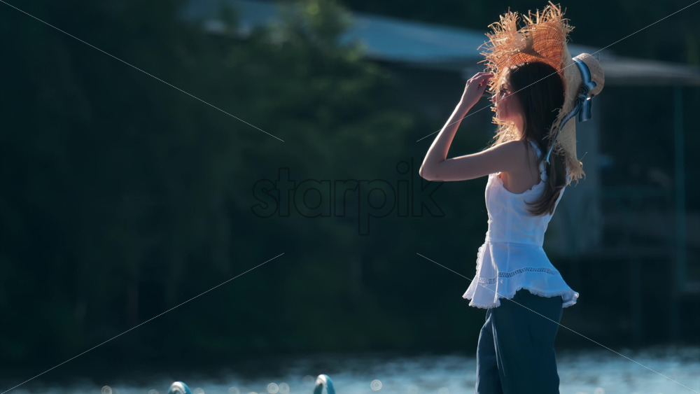 Chisinau, Moldova – June 17, 2025: Woman in a wide-brimmed straw hat with a ribbon, soaking in the late afternoon light - Starpik Stock